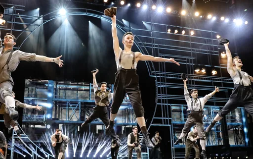 The cats of Newsies dancing on stage