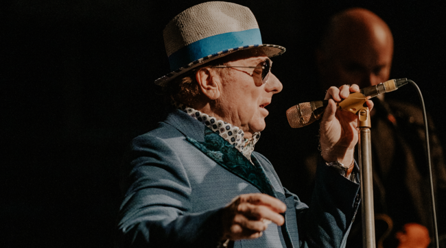 Van Morrison singing into a microphone on stage