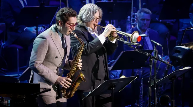 Guy Barker playing the trumpet on stage with guest